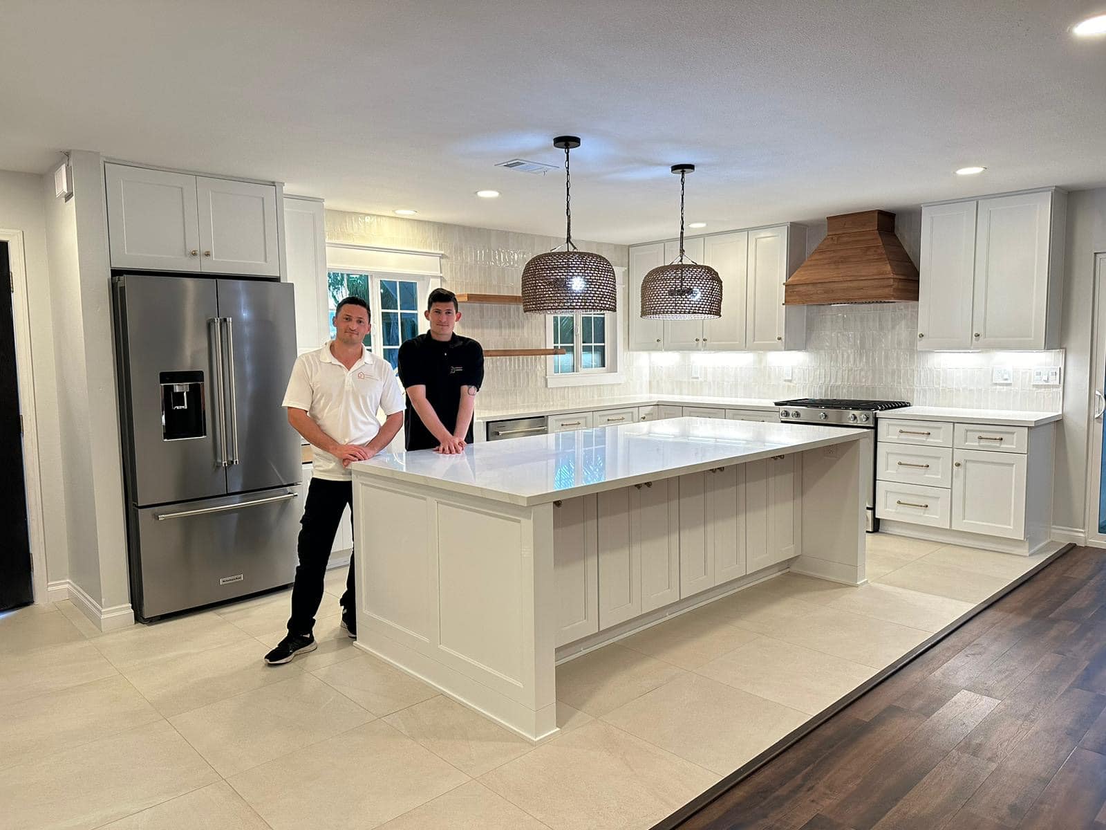Joseph and Didi Sheiner standing in a completed kitchen remodel with a marble-top island
