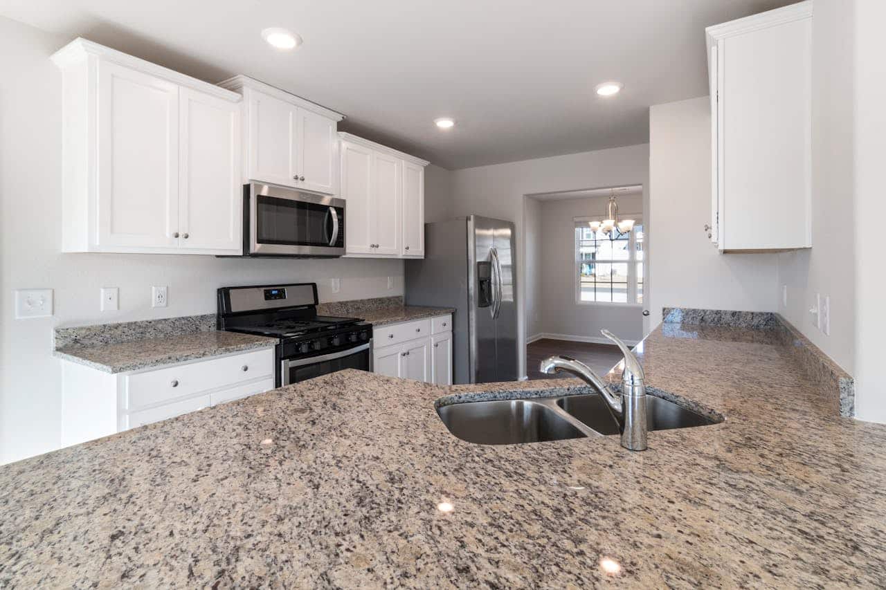 Kitchen with white shaker cabinets, a stainless steel range and granite countertops