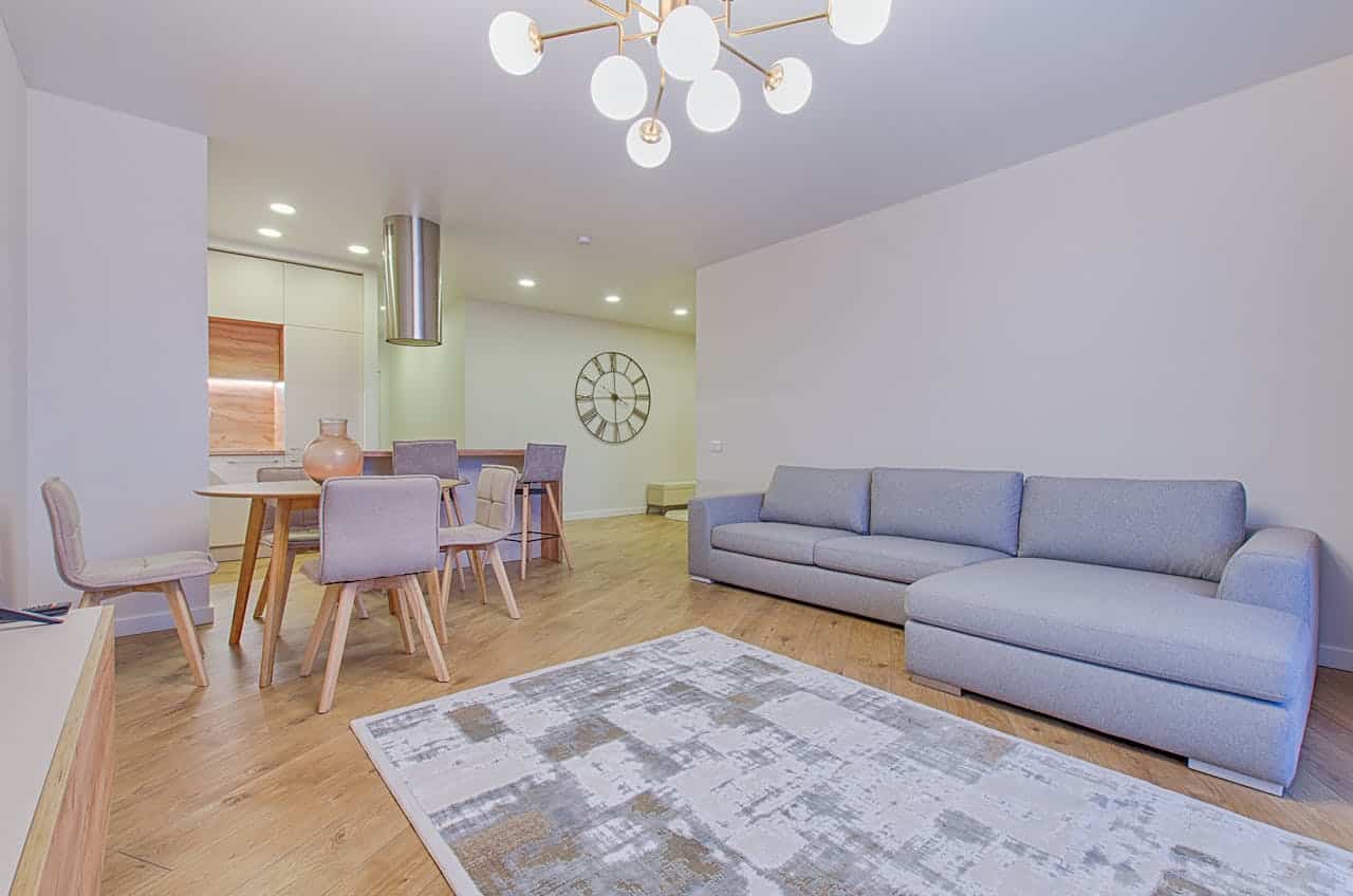 Open-plan living and dining area with a grey sofa, dining table and a pendant chandelier