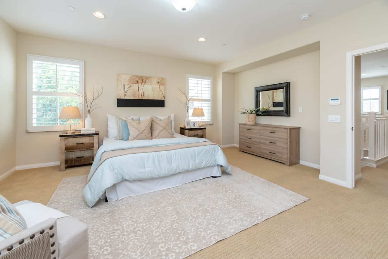 Master bedroom with an upholstered bed frame, dresser and soft lighting